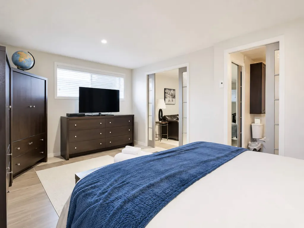 Chambre principale avec lit, commode et téléviseur